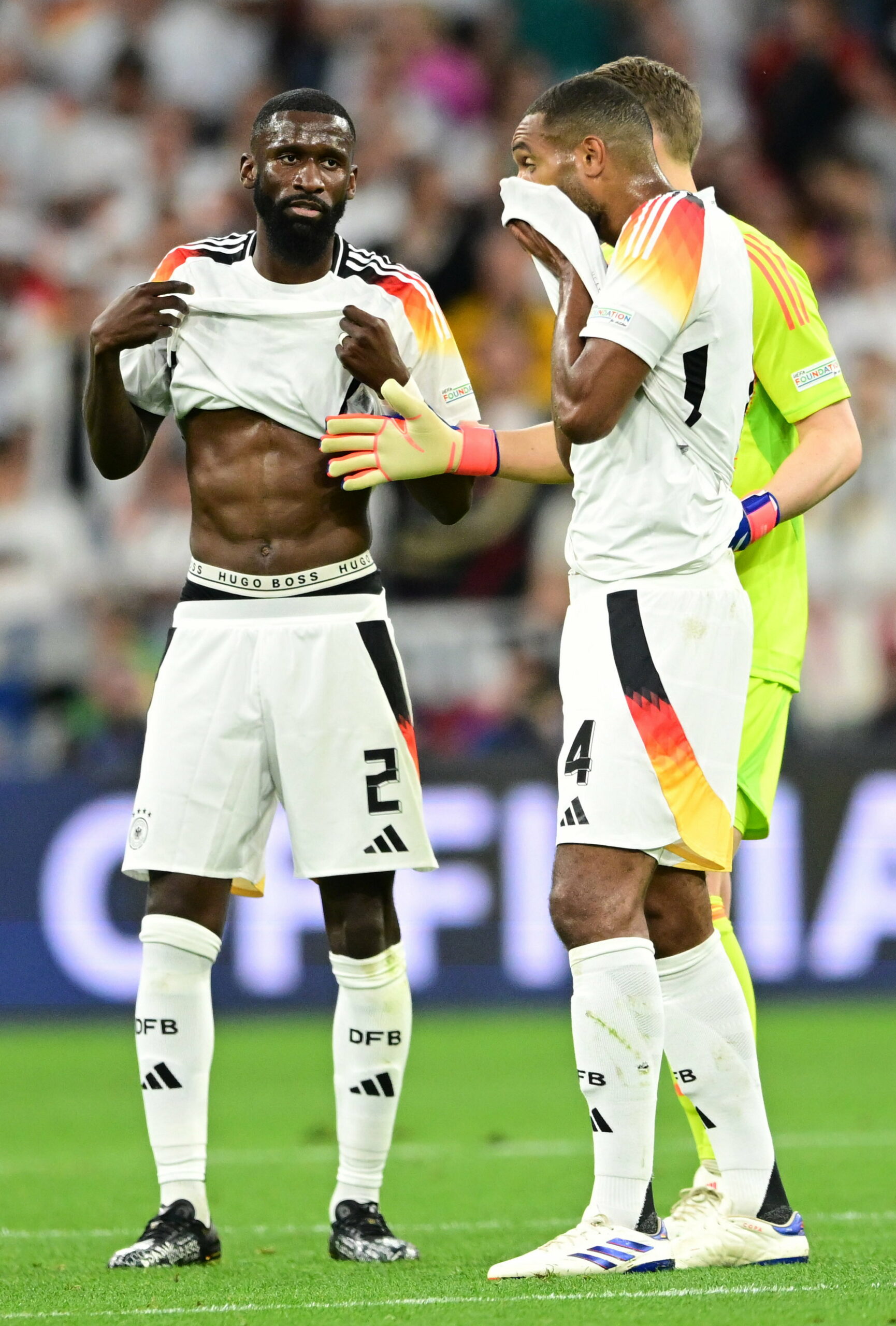 Antonio Rüdiger und Jonathan Tah ziehen jeweils ihr Trikot hoch, Rüdiger über den Bauch, Tah übers Gesicht.