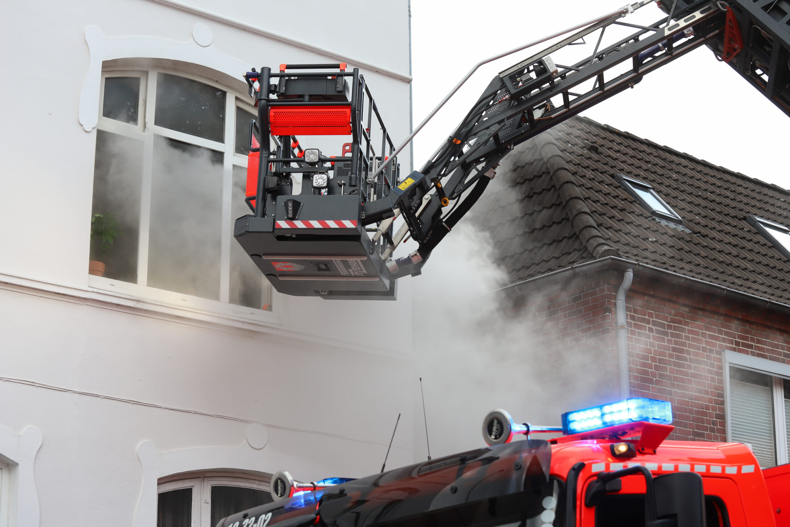 Drehleiter vor qualmendem Fenster