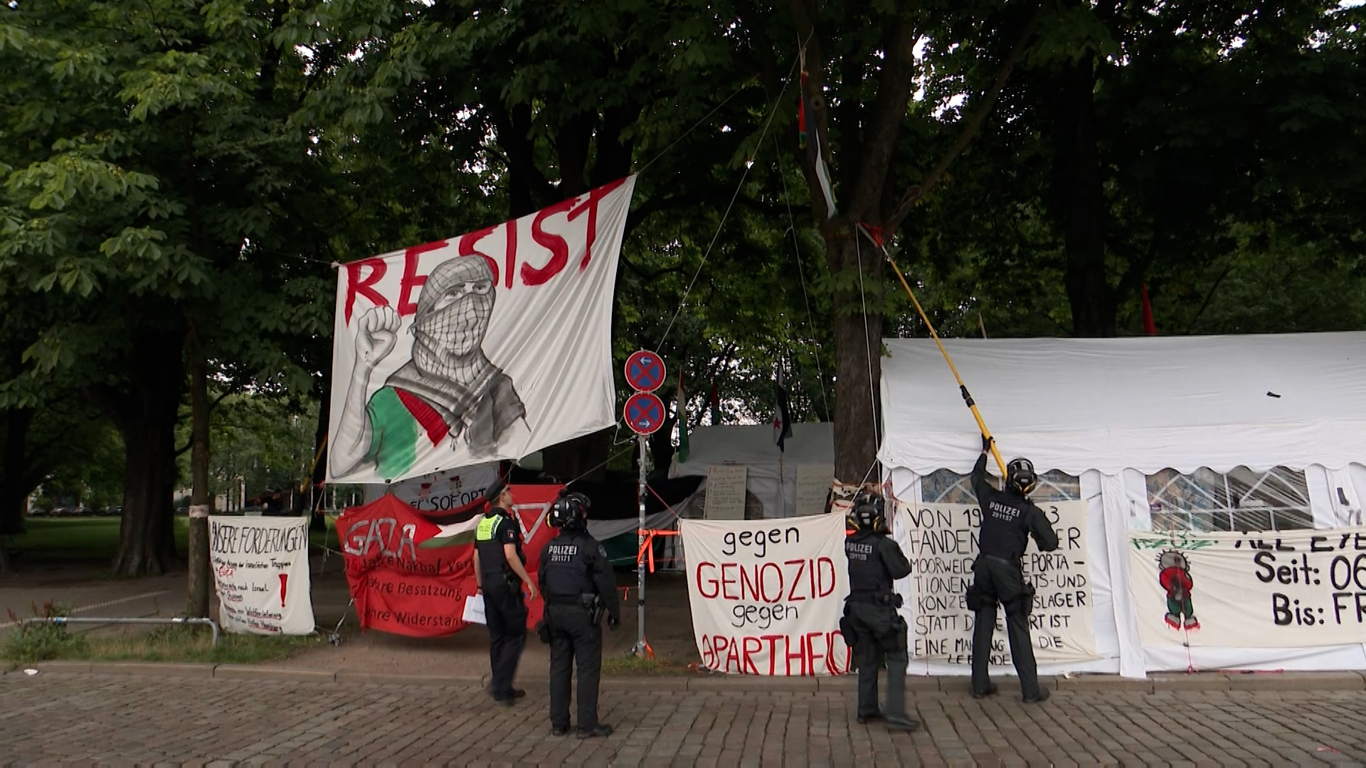 Polizisten hängen illegal angebrachte Banner am umstrittenen Palästina-Camp auf der Moorweide ab.