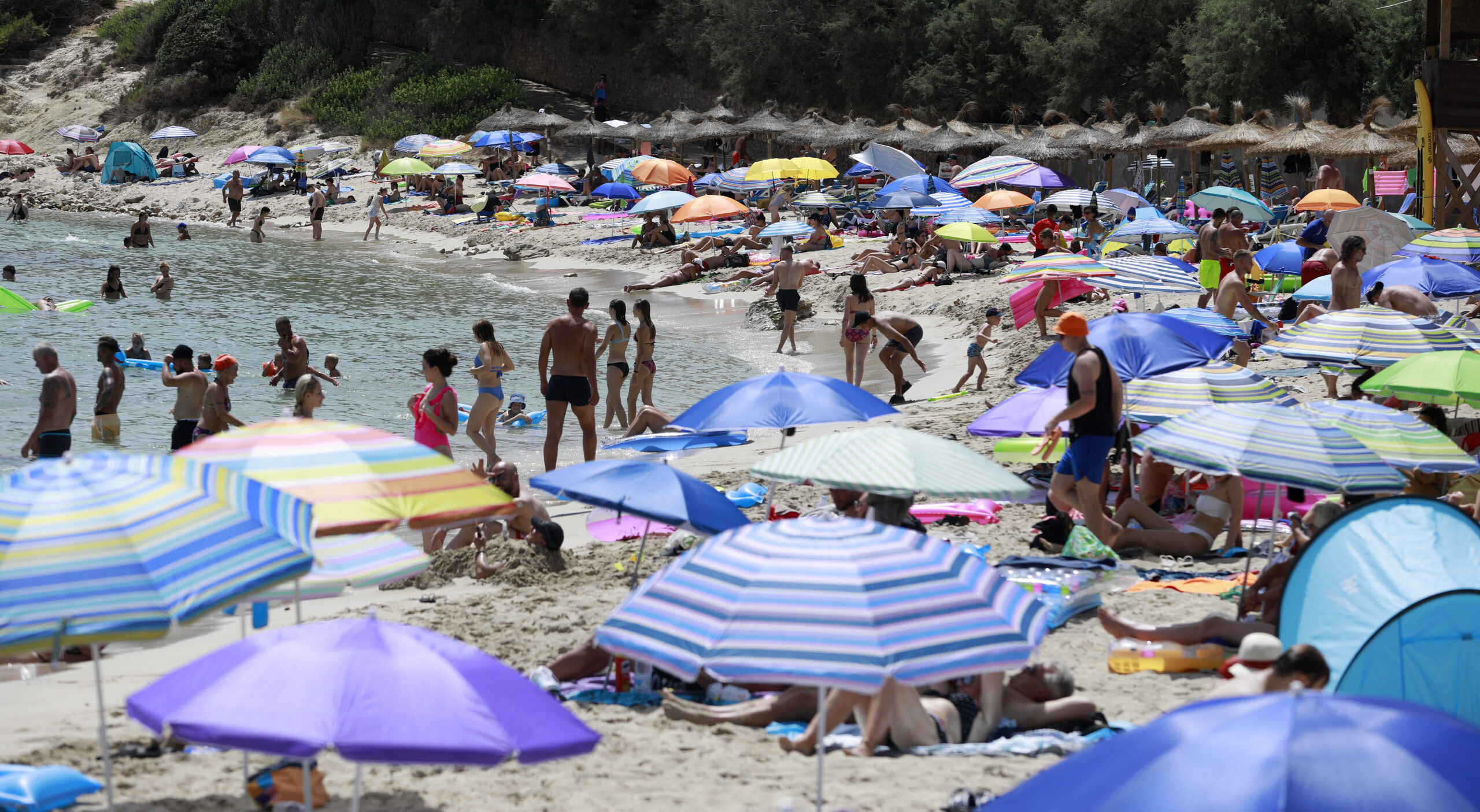 Menschen schwimmen und sonnen sich am Strand Cala Ratjada auf Mallorca.