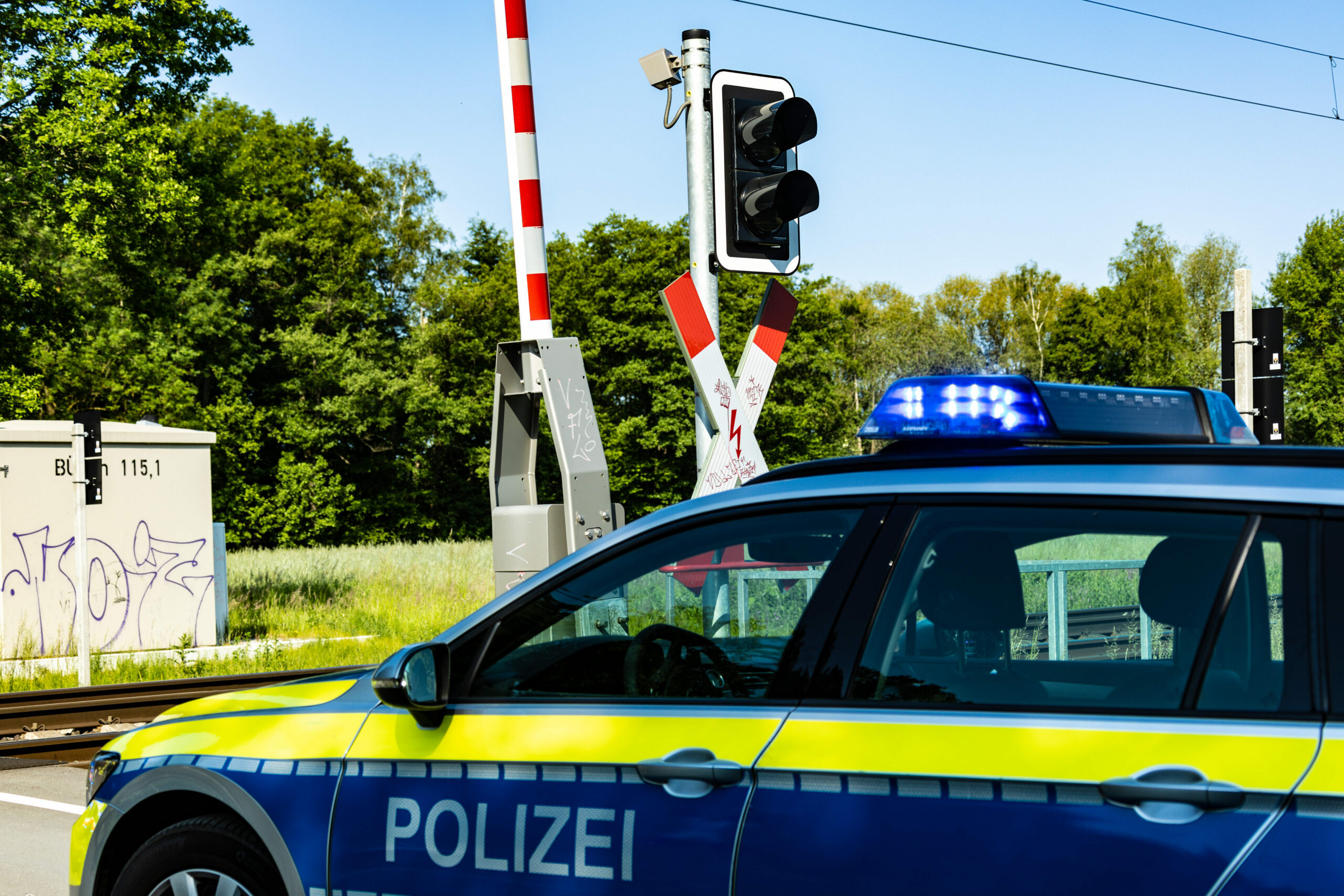 Ein Streifenwagen der Polizei steht vor einem Bahnübergang.