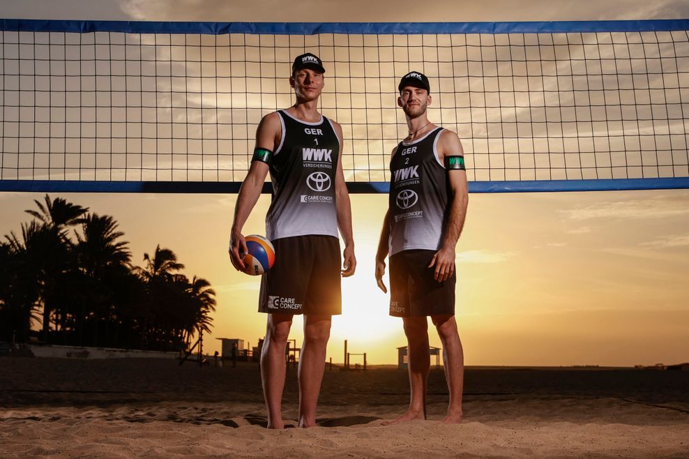 Nils Ehlers und Clemens Wickler stehen im Sonnenuntergang vor einem Beachvolleyballnetz