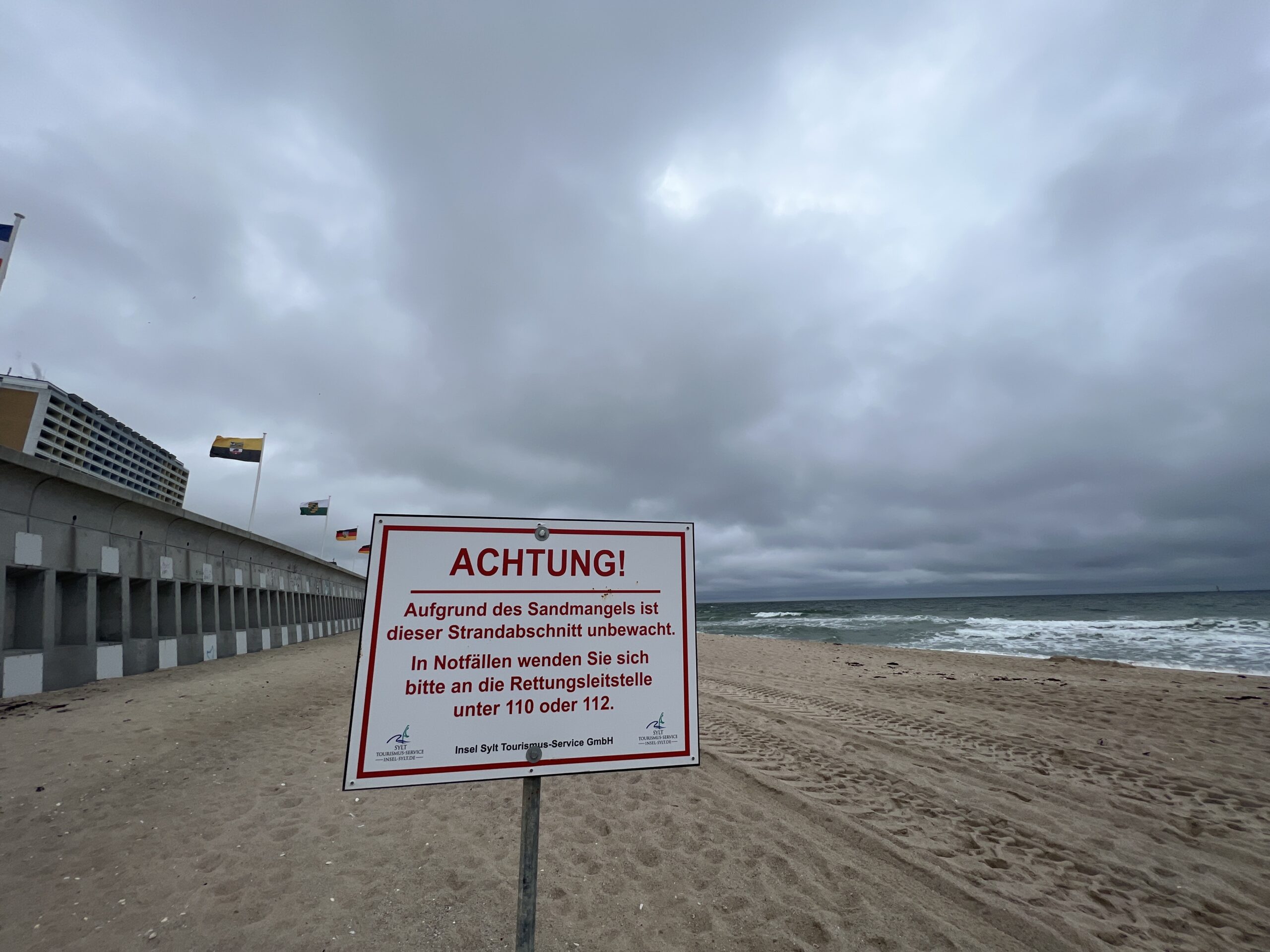 Ein Warnschild steht vor Strandkörben am Strand vor Westerland.