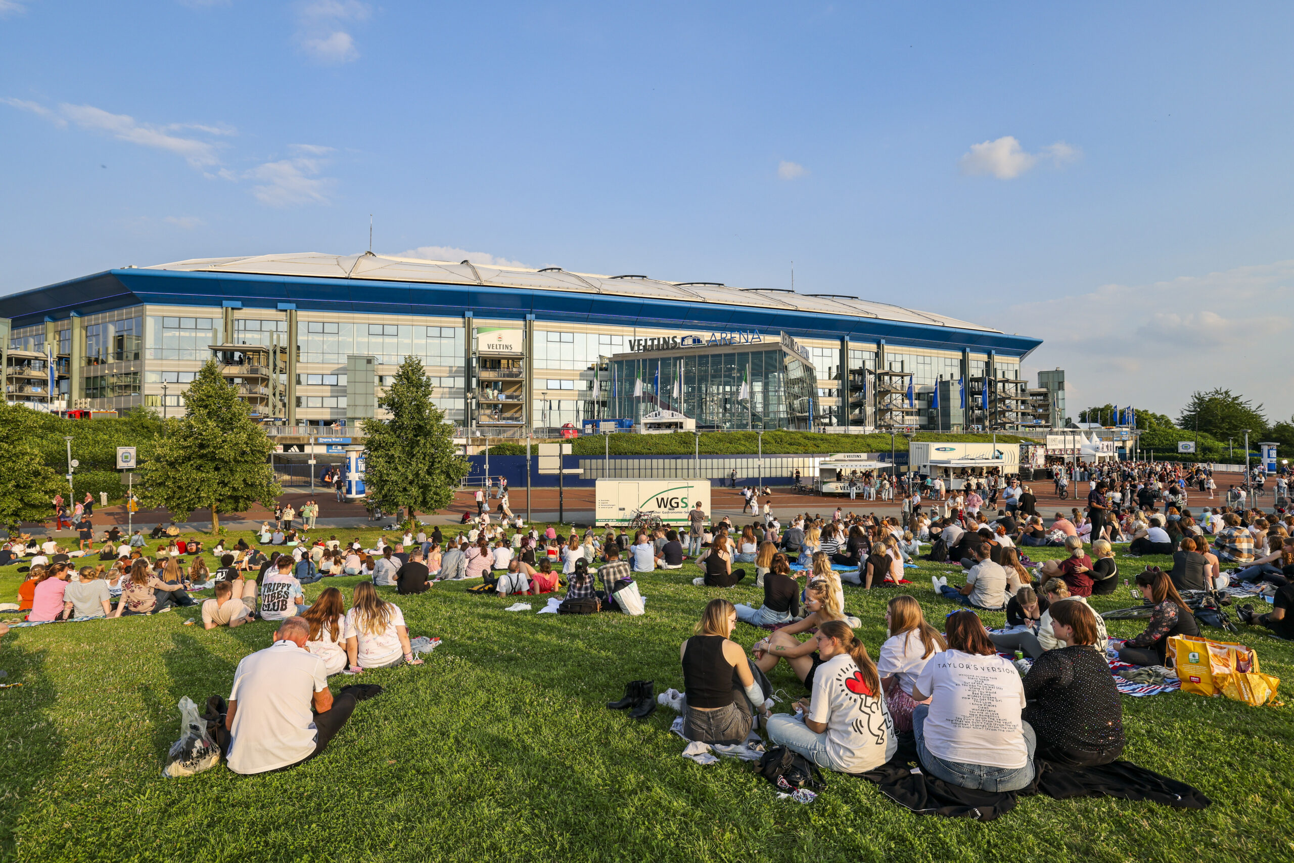 Menschen auf einer Wiese vor einem Stadion