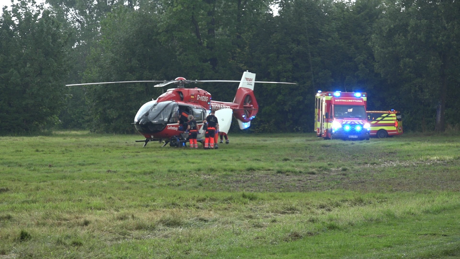 Rettungskräfte stehen bei einem Rettungshubschrauber und bereiten den Transport von Verletzten vor.