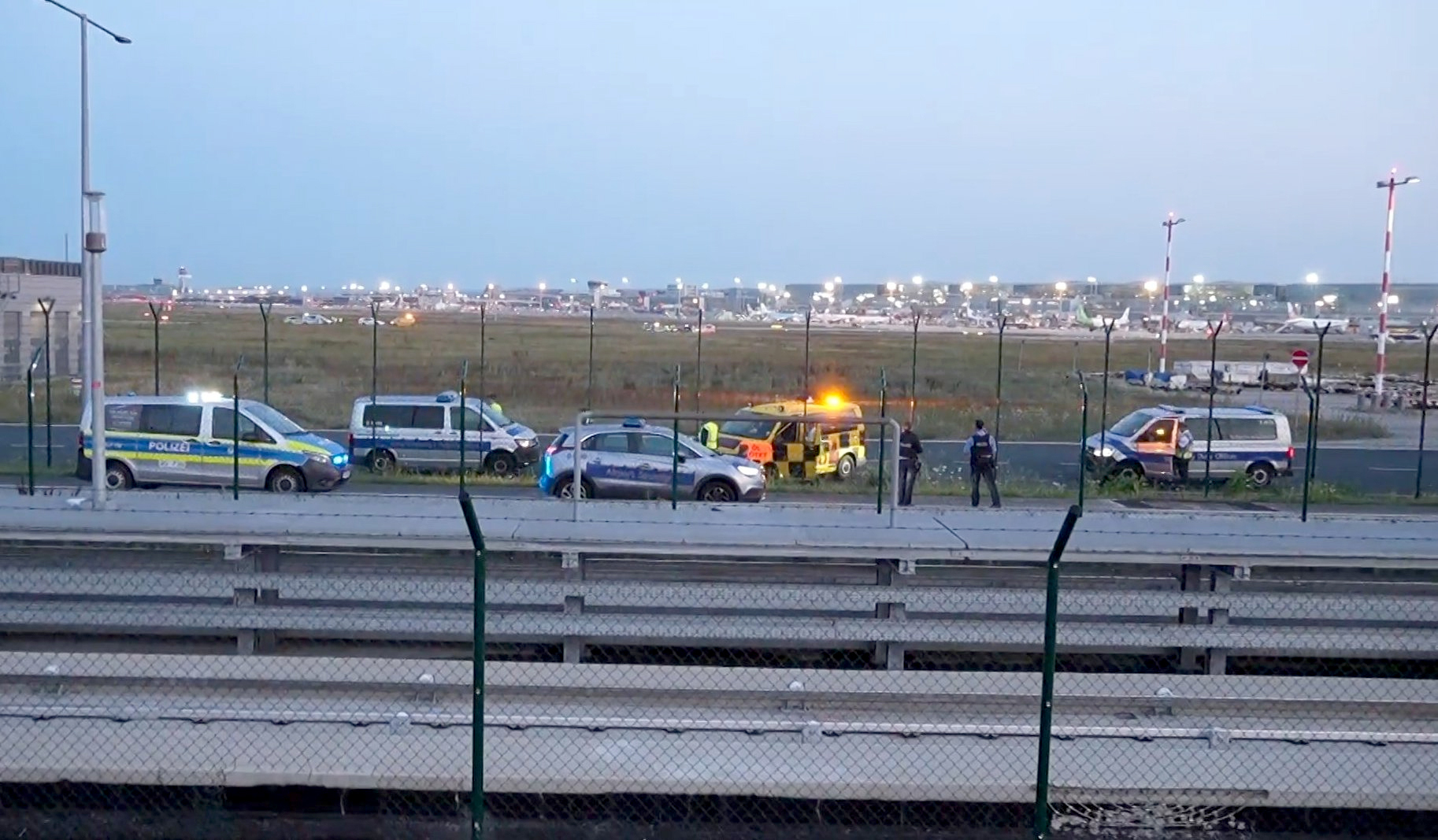 Einsatzfahrzeuge der Polizei stehen unweit des Rollfelds am Frankfurter Flughafen. Wegen einer Aktion von Klimaaktivisten ist der Flugverkehr vorläufig eingestellt worden.