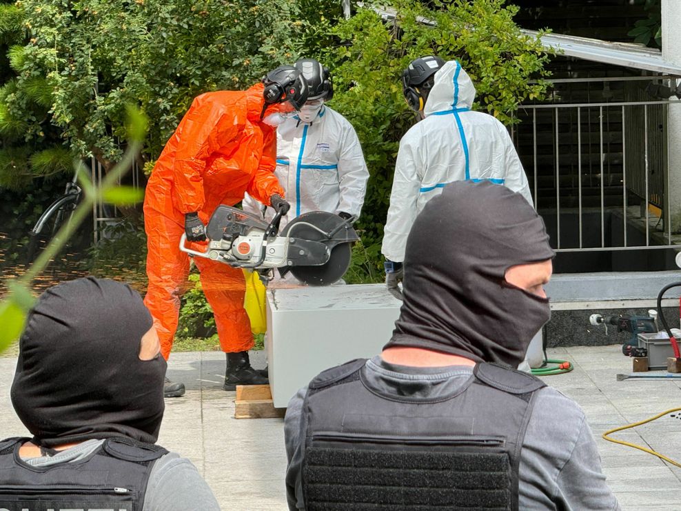 Polizeibeamte flexen einen Tresor auf, der beim IZH beschlagnahmt wurde.