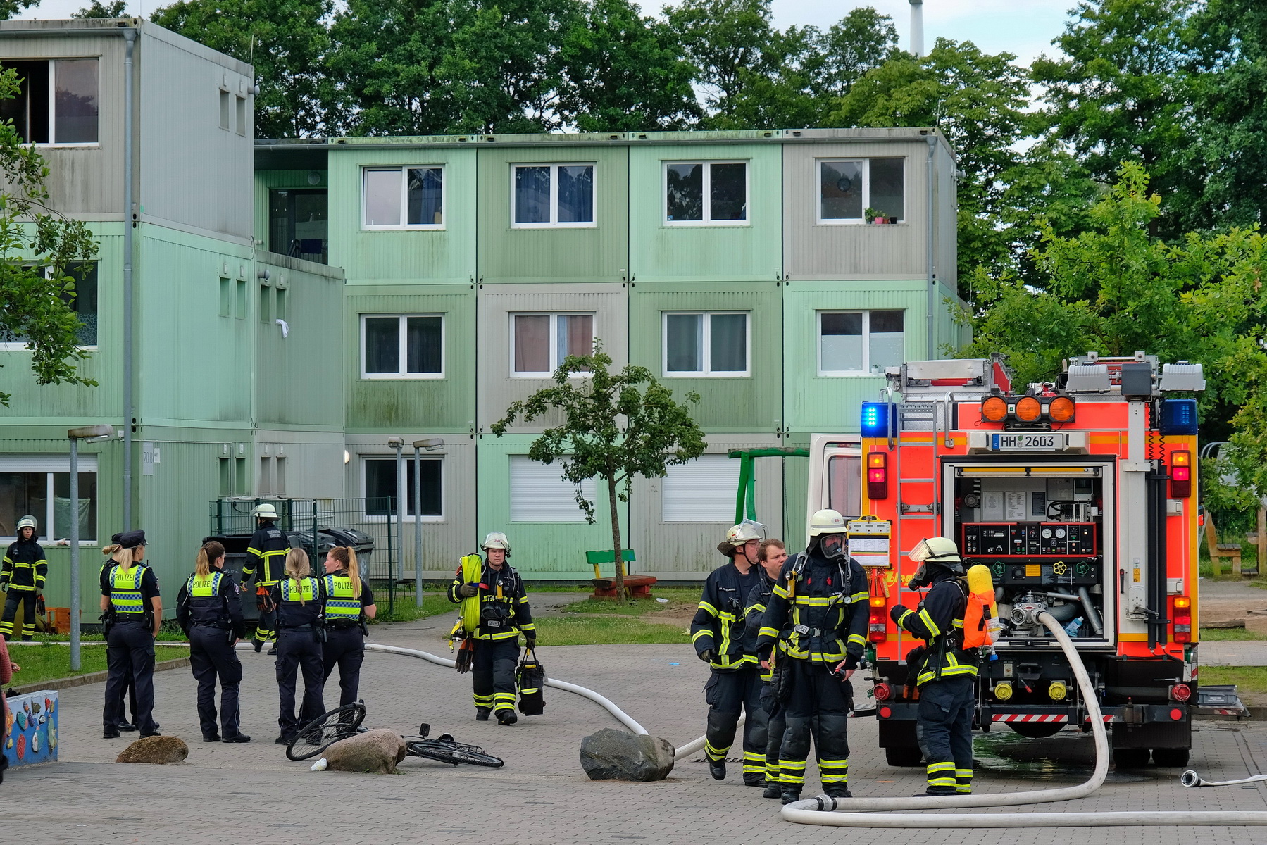 Feuerwehrleute stehen vor der Flüchtlingsunterkunft.