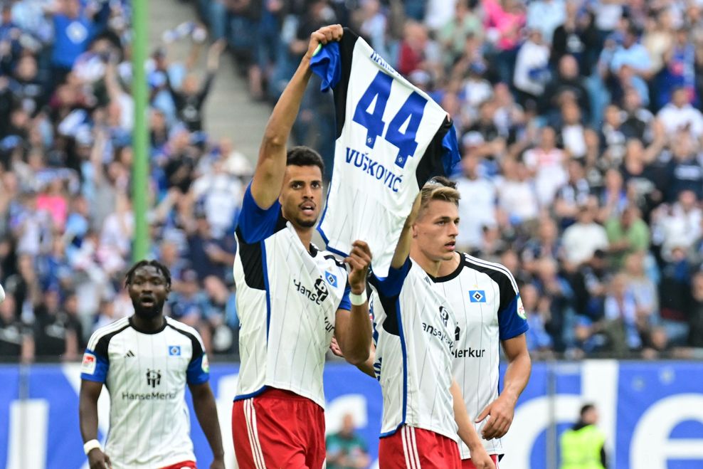 Robert Glatzel und Miro Muheim halten auf dem Spielfeld ein Trikot von Mario Vuskovic hoch