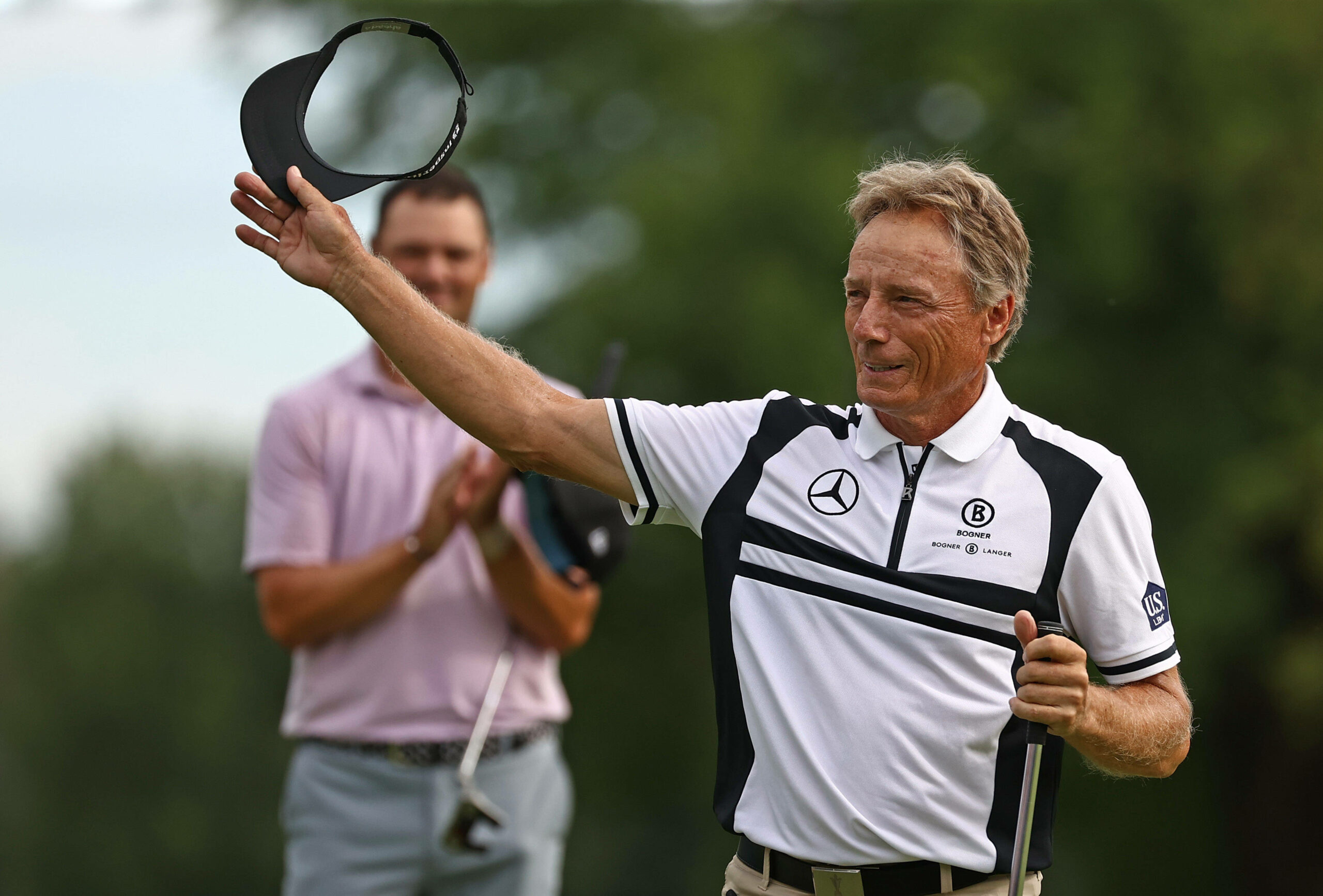 Bernhard Langer hebt bei den BMW International Open 2024 seine Kopfbedeckung in die Luft