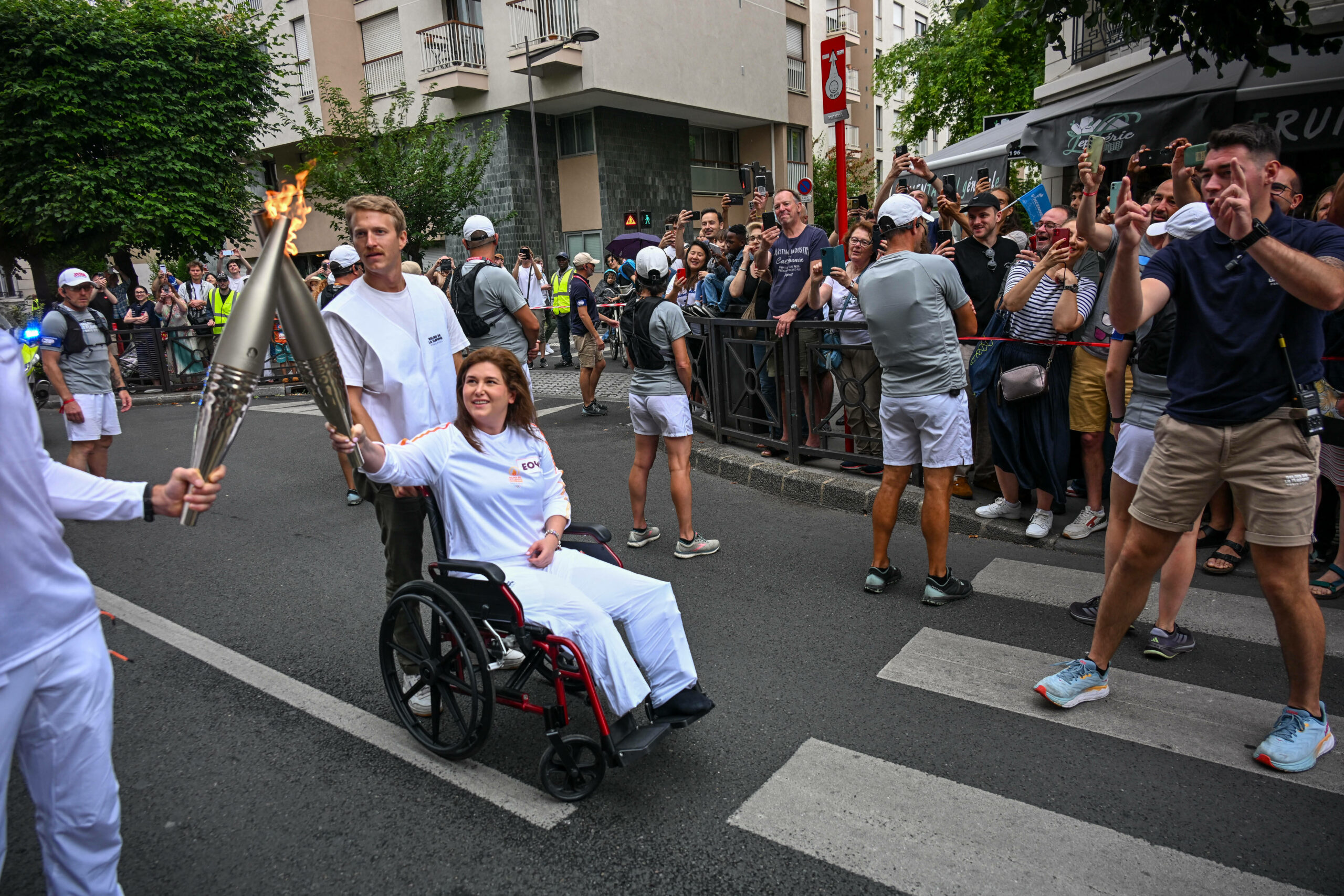 AFP-Journalistin Christina Assi mit olympischer Fackel im Rollstuhl