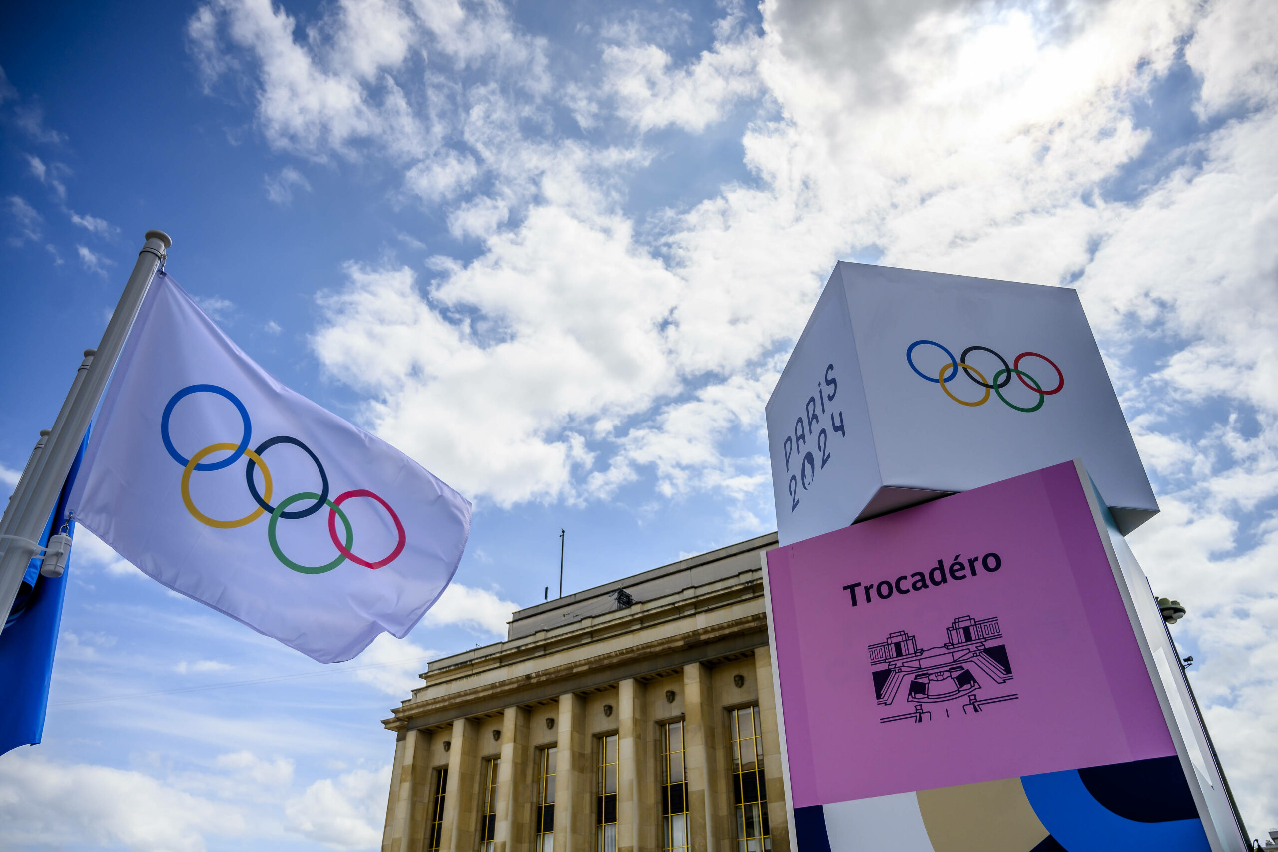 Weiße Fahne und Aufsteller mit den olympischen Ringen drauf.