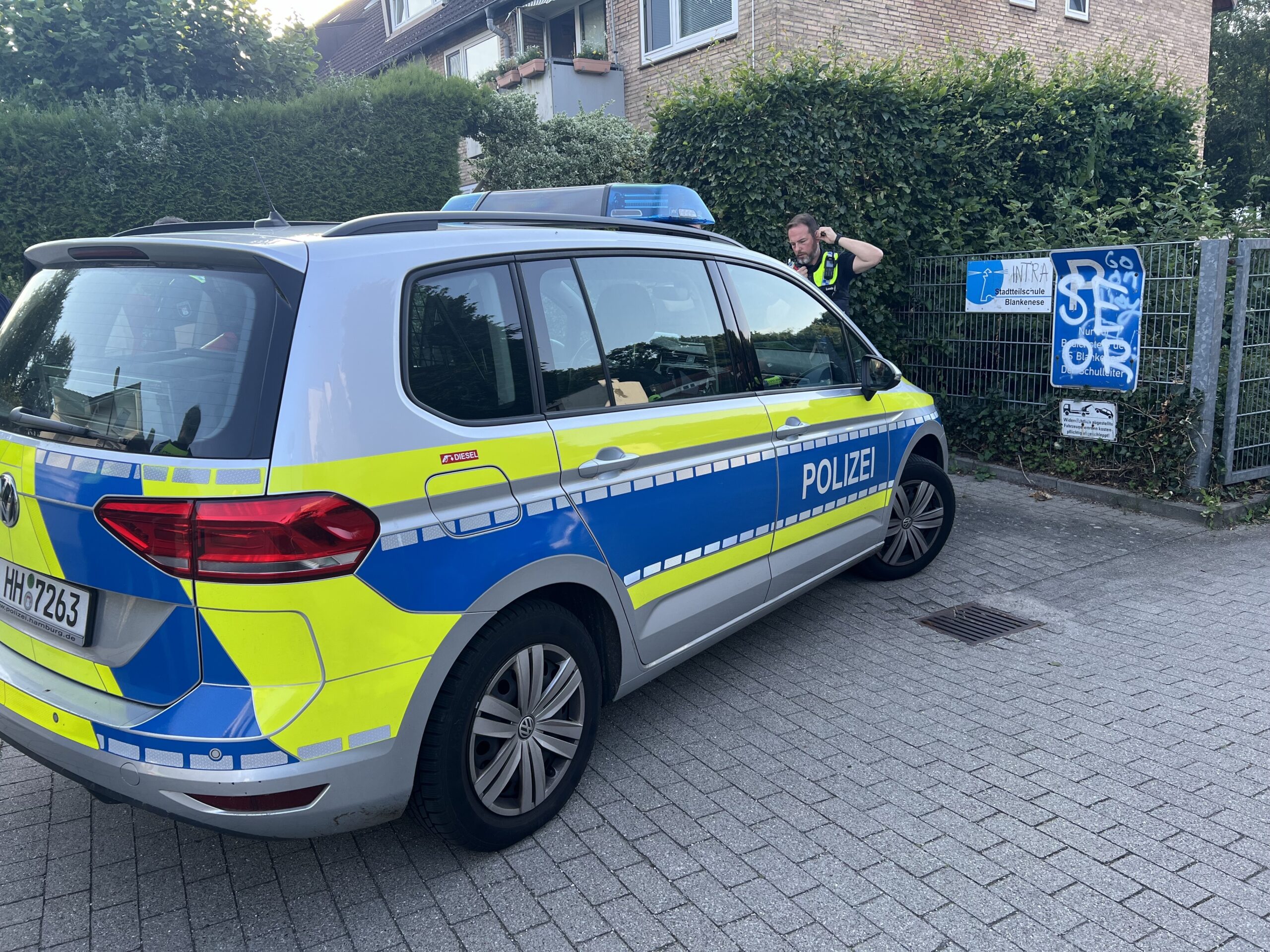 Ein Polizeiwagen steht vor der Einfahrt der Schule.