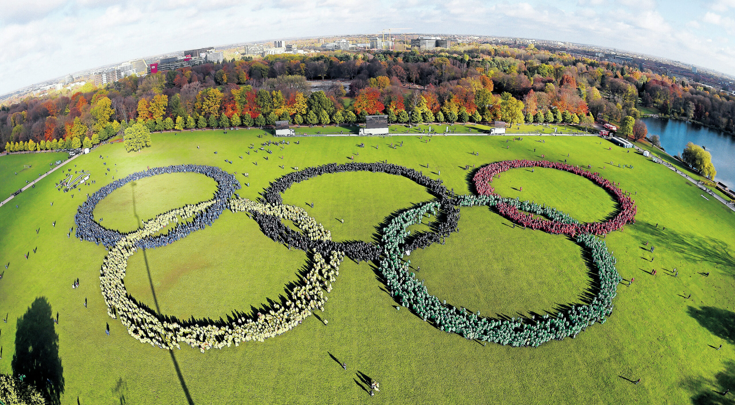 Bunt gekleidete Hamburger bilden im Stadtpark die fünf Olympischen Ringe.