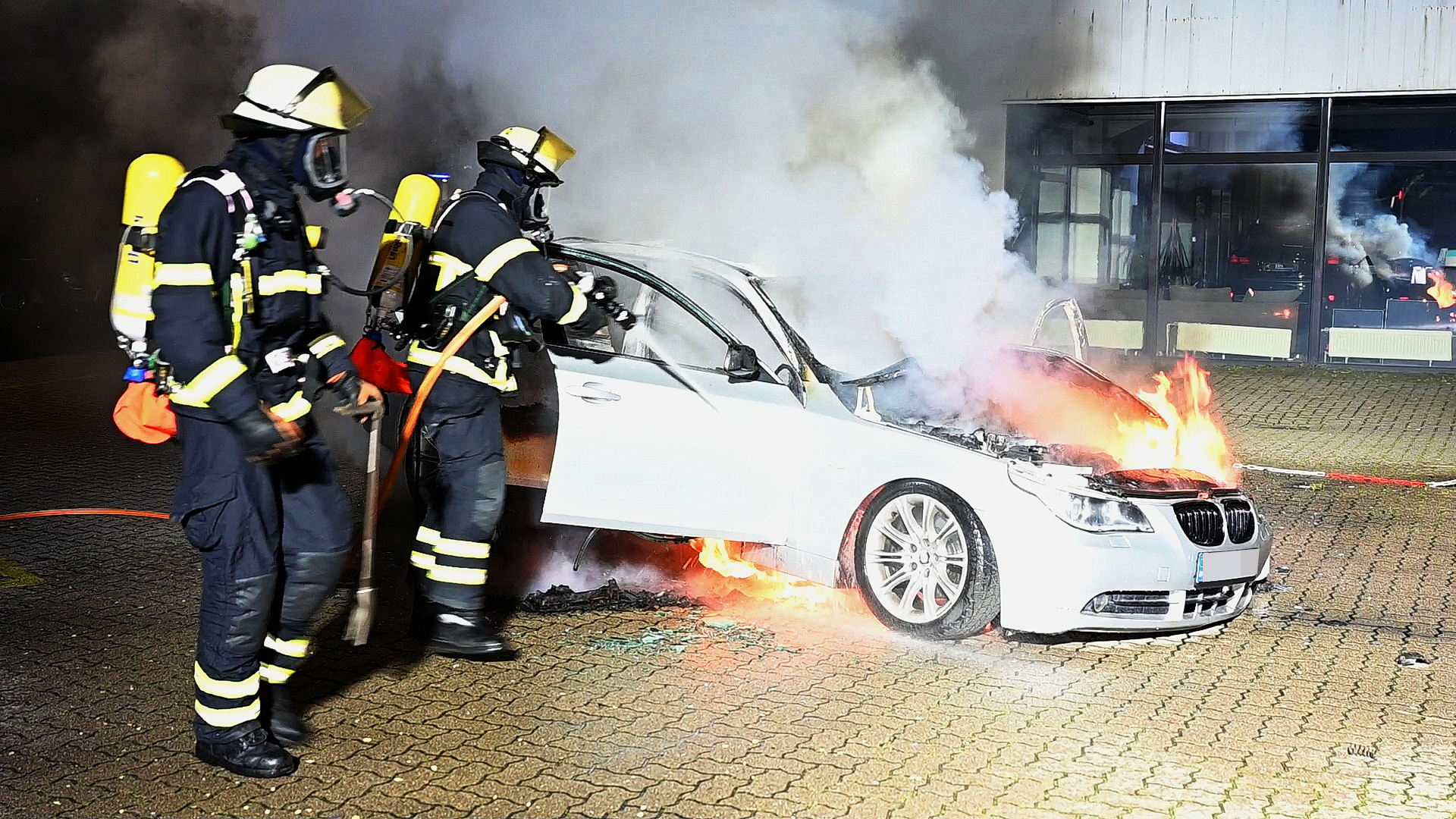 Feuerwehrleute löschen einen brennenden BMW.