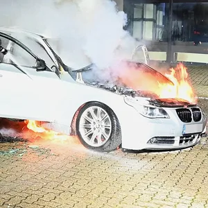 Feuerwehrleute löschen einen brennenden BMW.