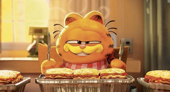 Szene aus dem Animationsfilm Garfield: Der Kater sitzt mit Messer und Gabel in den Pfoten vor drei Portionen Lasagne.