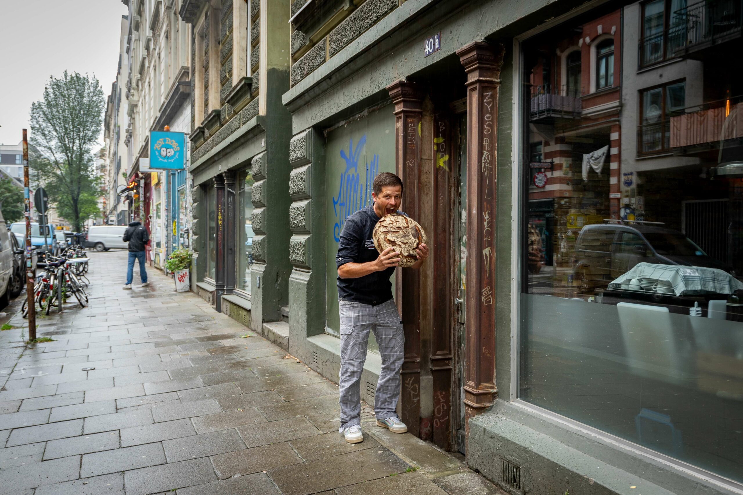 Tim Lessau beißt vor Laden in Brot