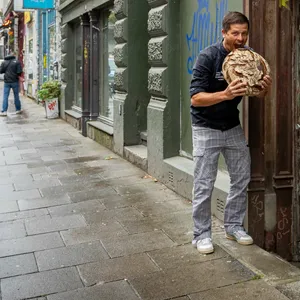 Tim Lessau beißt vor Laden in Brot