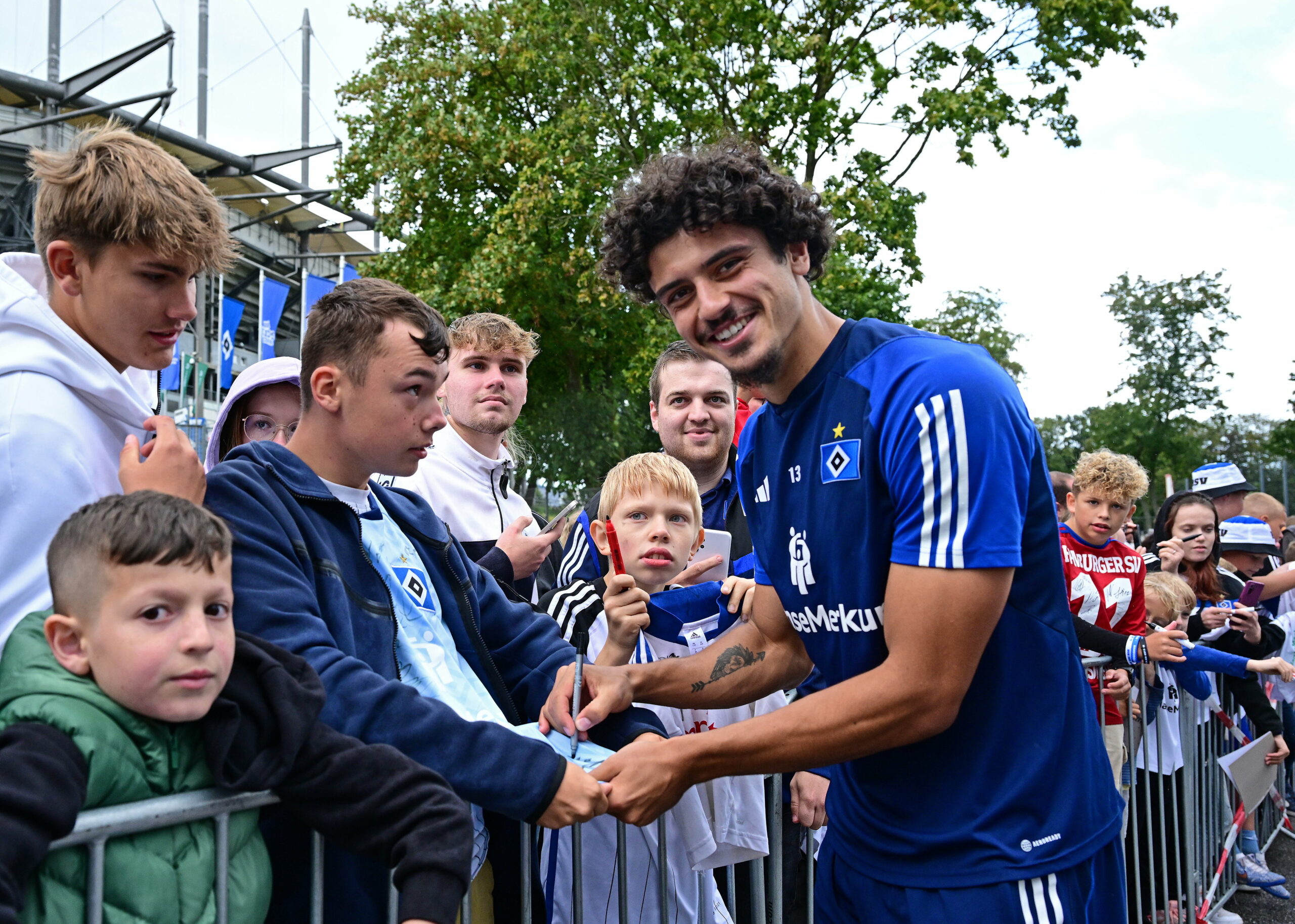 Guilherme Ramos schreibt im Volkspark Autogramme und lächelt in die Kamera.