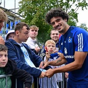 Guilherme Ramos schreibt im Volkspark Autogramme und lächelt in die Kamera.