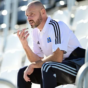 Heiko Westermann sitzt auf einer Tribüne und spricht in sein Telefon.