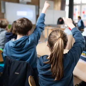 Schülerinnen und Schüler einer fünften Klasse eines Gymnasiums melden sich im Unterricht.