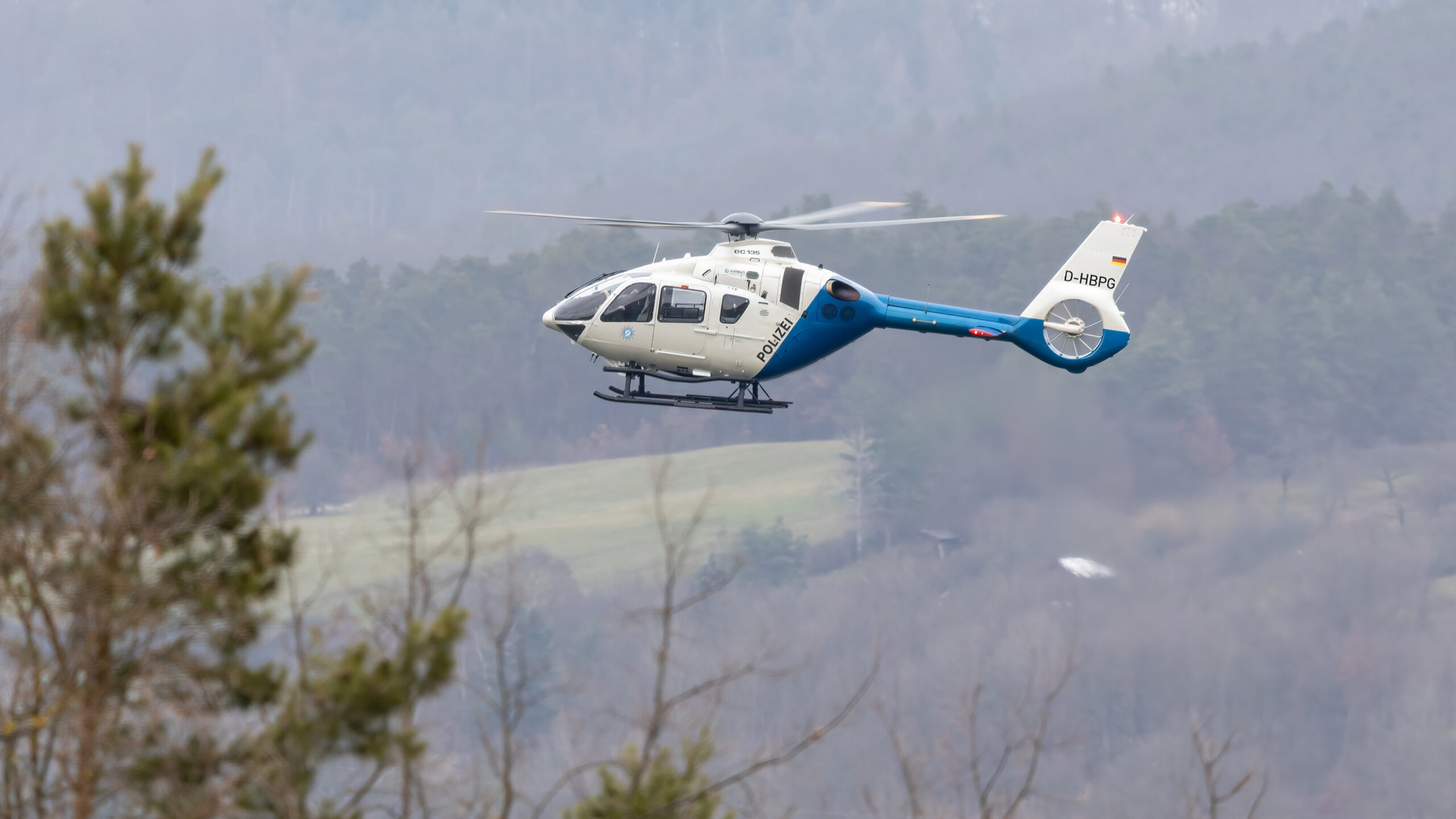 Polizeihubschrauber im Einsatz über einem Wald