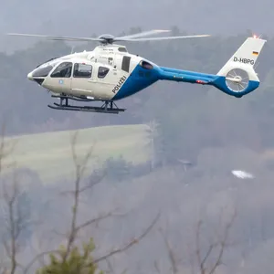 Polizeihubschrauber im Einsatz über einem Wald