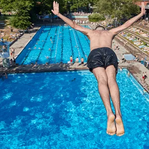 Ein Mann springt vom Zehnmeter Turm in das Becken im Sommerfreibad Kaifu-Bad.