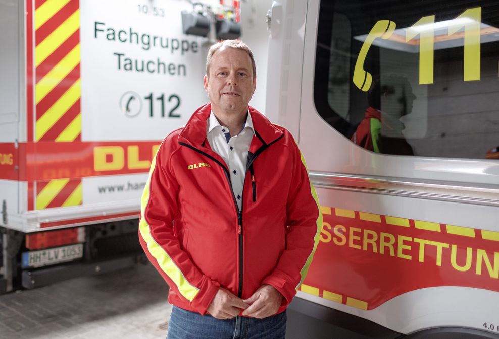 Heiko Mählmann, Präsident der Deutschen Lebens-Rettungs-Gesellschaft Landesverband Hamburg e. V. steht vor Rettungsfahrzeugen in der DLRG-Zentrale.