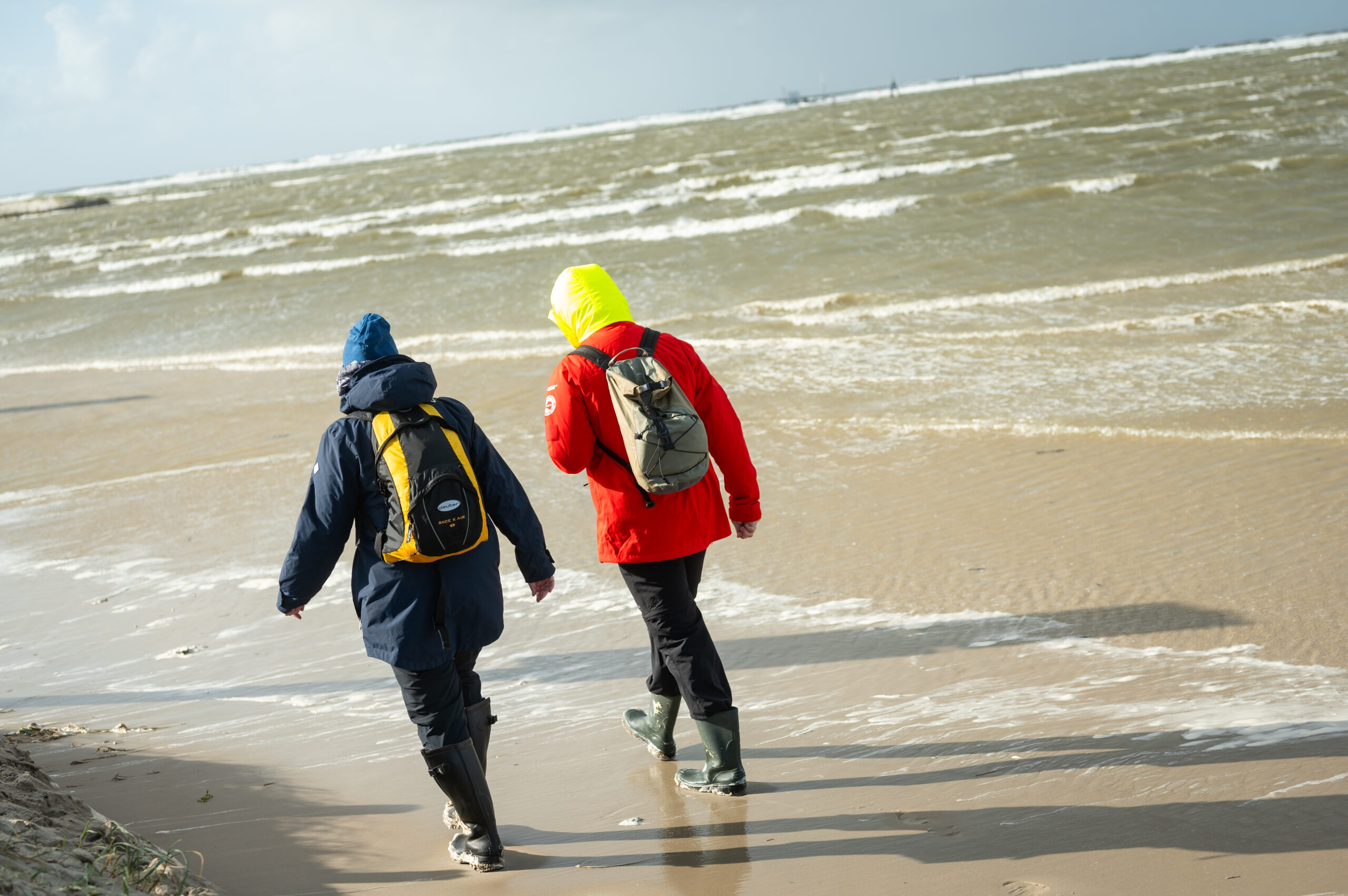 Spaziergänger gehen am überfluteten Strand an der Nordsee.