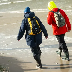 Spaziergänger gehen am überfluteten Strand an der Nordsee.