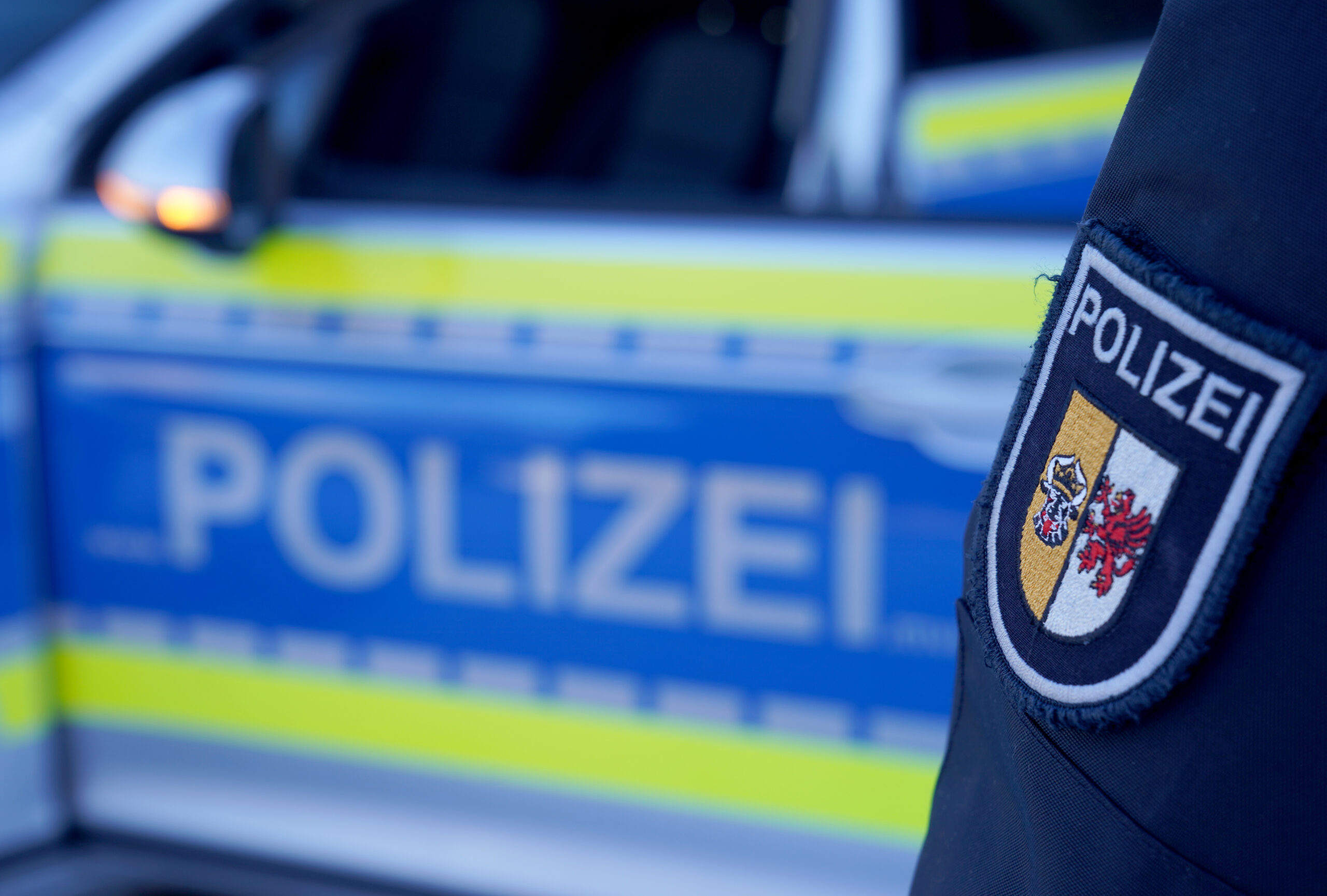 Eine Beamtin der Polizei Mecklenburg-Vorpommern steht neben einem Einsatzfahrzeug.