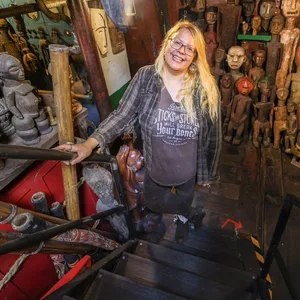 Die Kuratorin von „Harrys Hafenbasar“, Carolin Uhde, steht inmitten von asiatischen, südamerikanischen und afrikanischen Statuen.