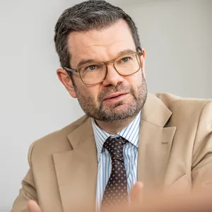 Ein dunkelhaariger Mann in hellem Anzug