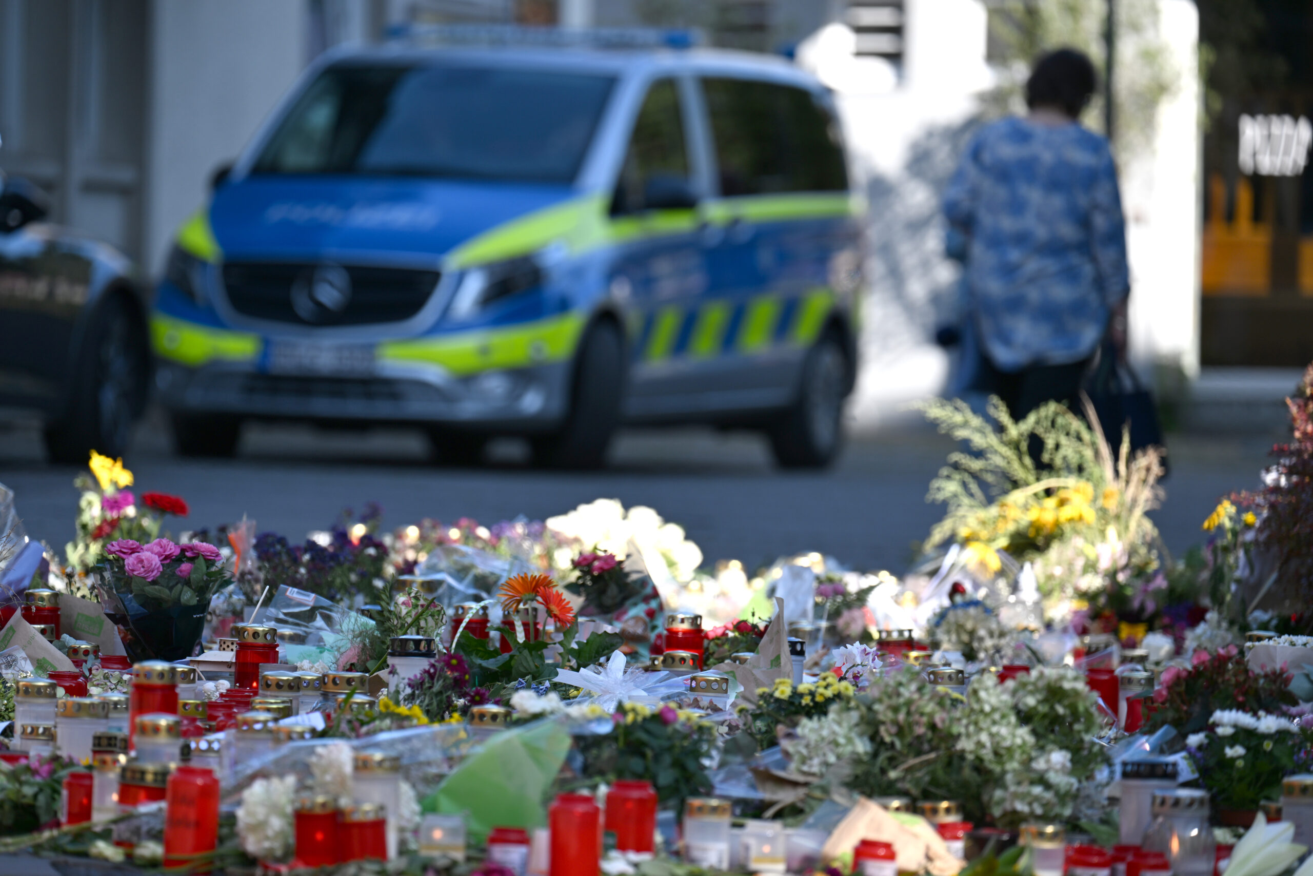 Gedenkstätte mit Blumen, im Hintergrund ein Polizeiauto