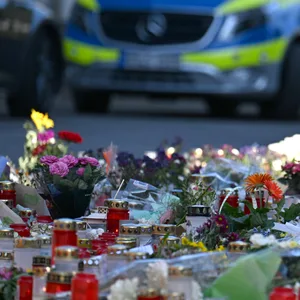 Gedenkstätte mit Blumen, im Hintergrund ein Polizeiauto