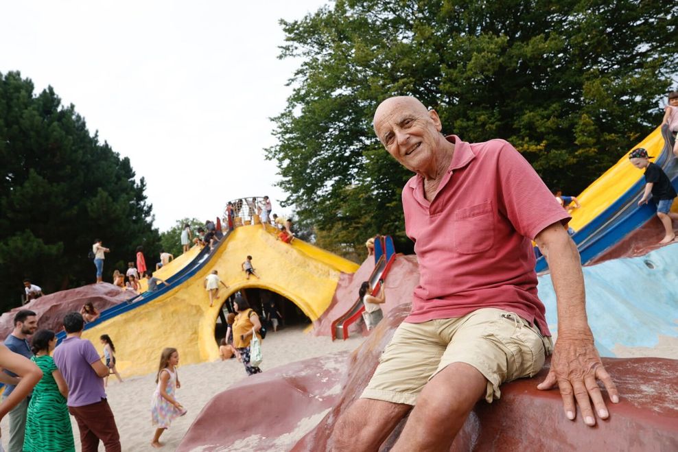 Mann sitzt vor Kletterhügeln auf einem Spielplatz