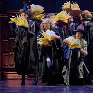 Mehrere Schauspieler stehen bei einer Szene von „Harry Potter und das verwunschene Kind“ mit geöffneten Büchern auf der Bühne.