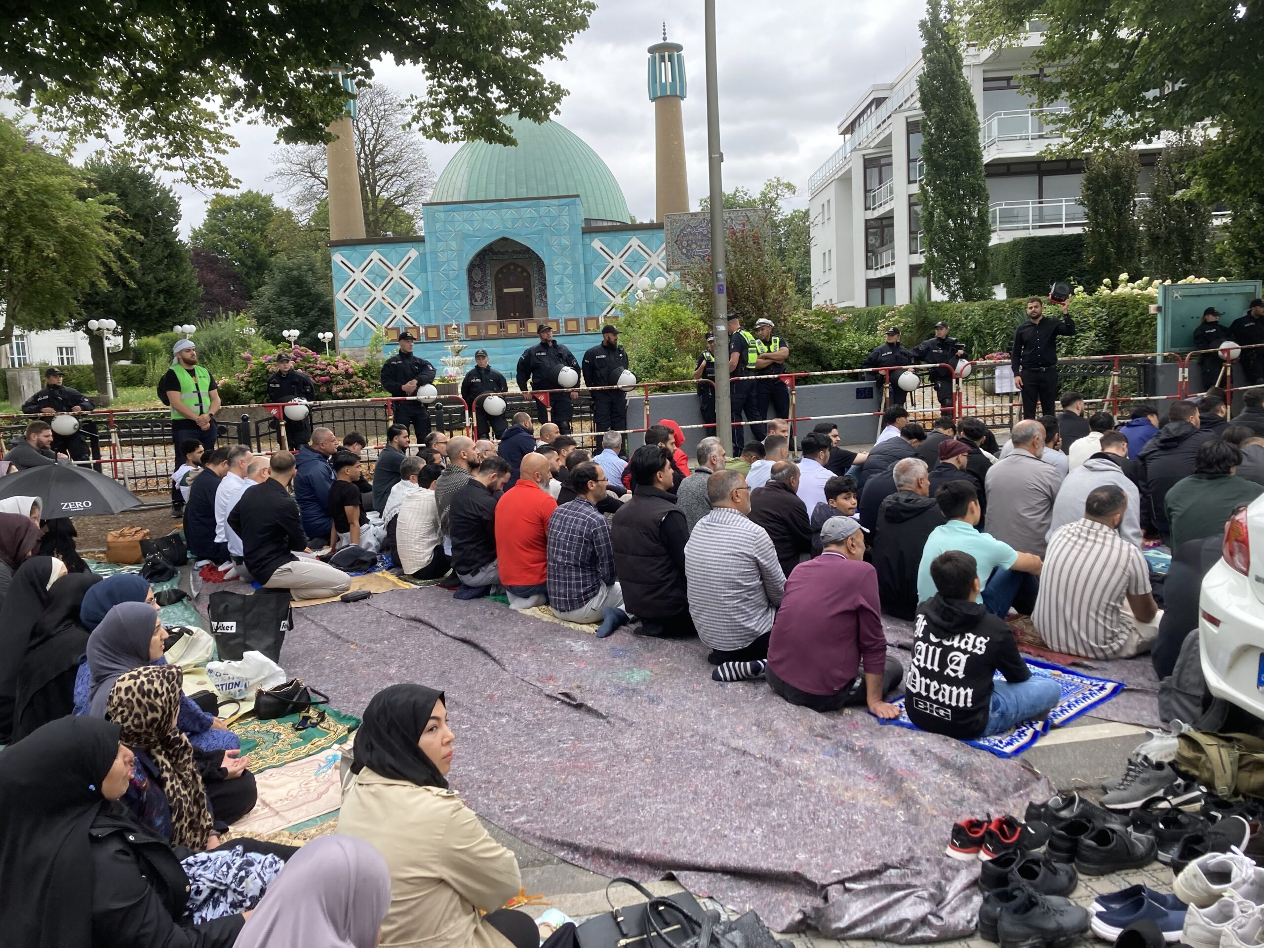 Gläubige sitzen zum Freitagsgebet vor der geschlossenen Blauen Moschee an der Alster in Hamburg.