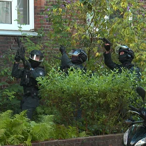 Mit gezogenen Waffen stehen USE-Einsatzkräfte vor einem Haus in Barmbek.