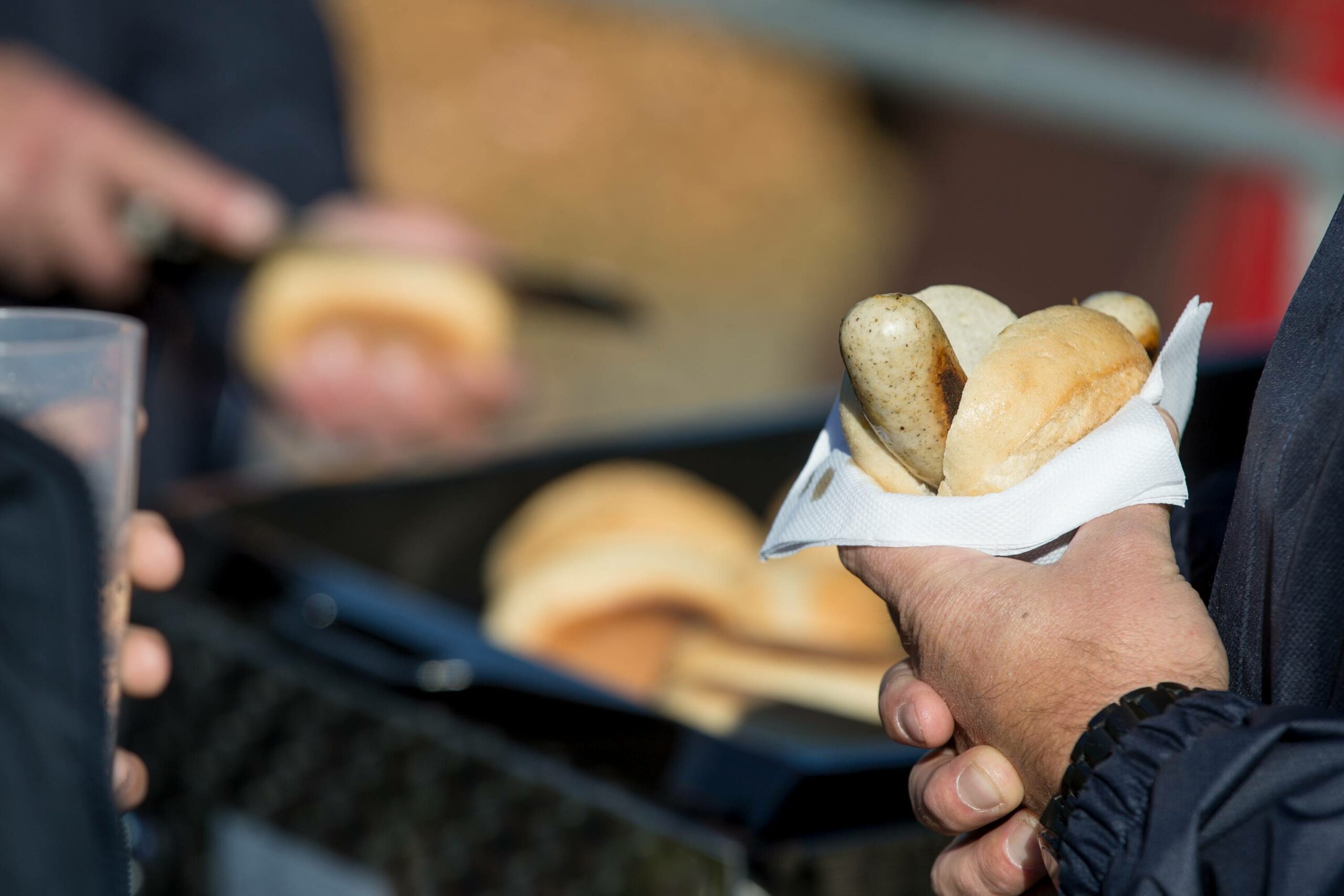 Ein Mann hält eine Bratwust im Brötchen in der Hand