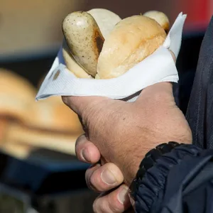 Ein Mann hält eine Bratwust im Brötchen in der Hand