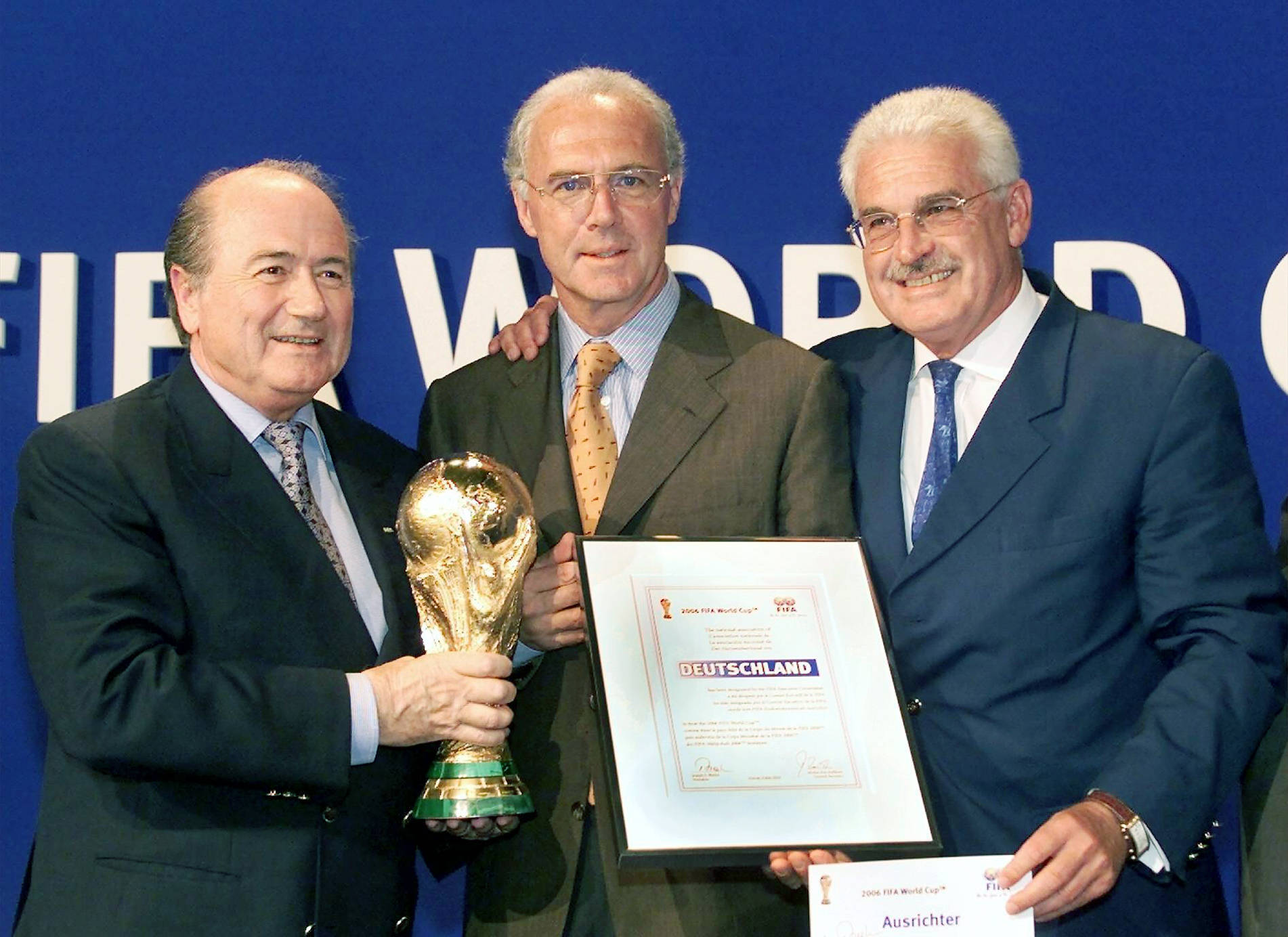 FIFA-Präsident Sepp Blatter (l.) übergibt die Ausrichterurkunde zur WM 2006 an DFB-Vizepraesident Franz Beckenbauer (M.) und DFB-Koordinator Fedor Radmann.