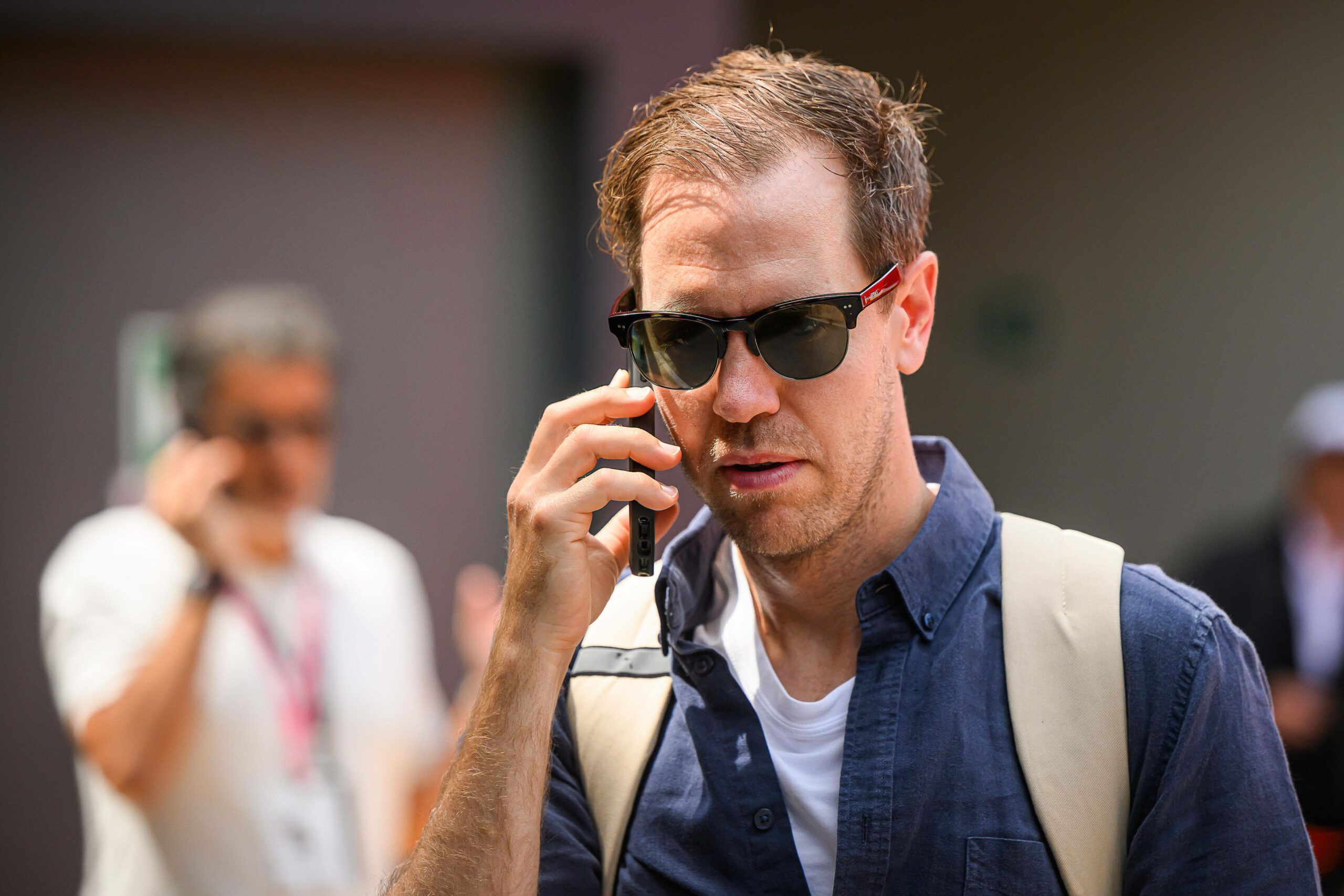 Sebastian Vettel mit Sonnenbrille auf am telefonieren.