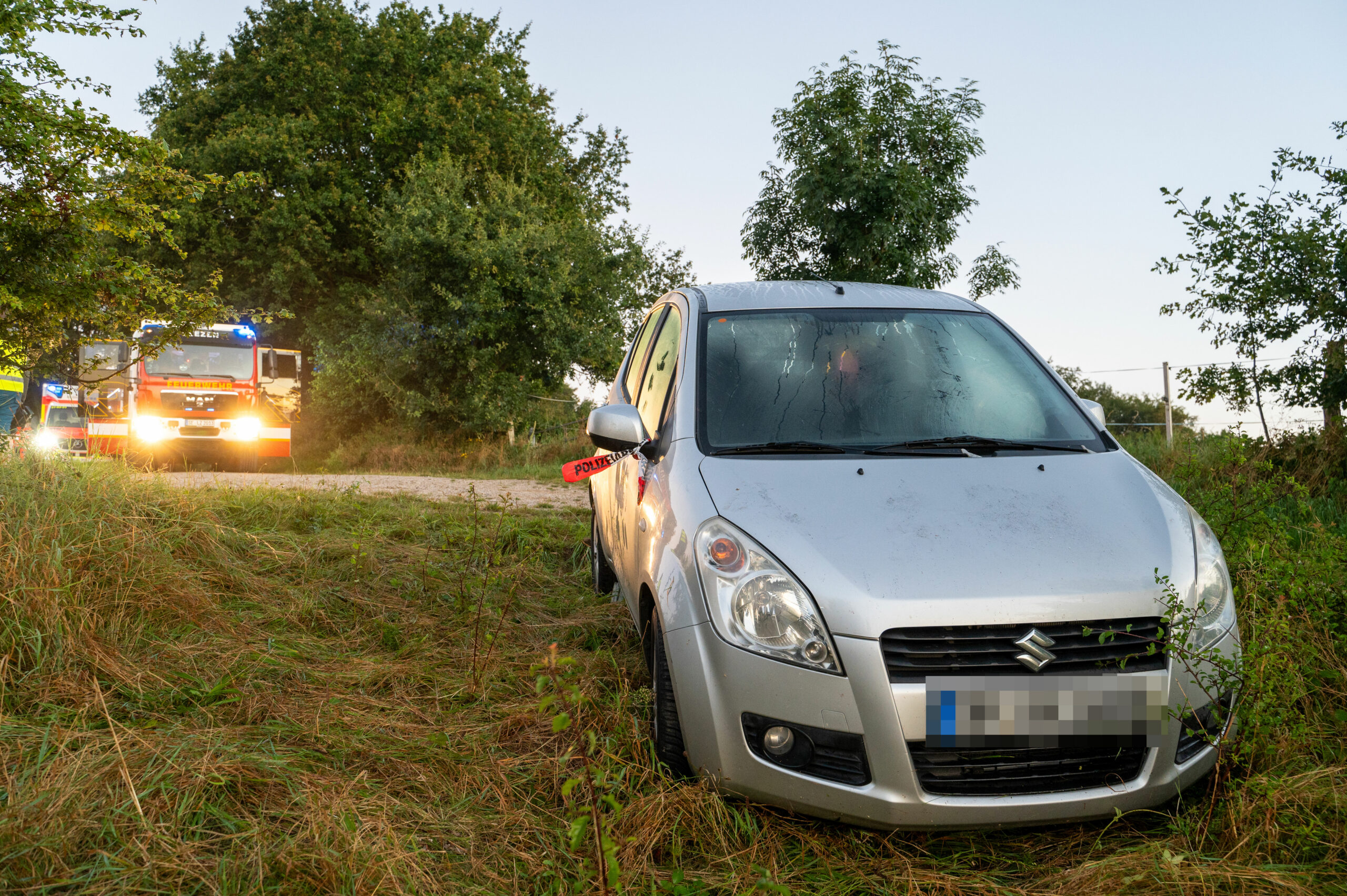 Silbernes Auto mit Feuerwehrautos im Hintergrund