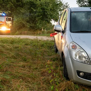 Silbernes Auto mit Feuerwehrautos im Hintergrund