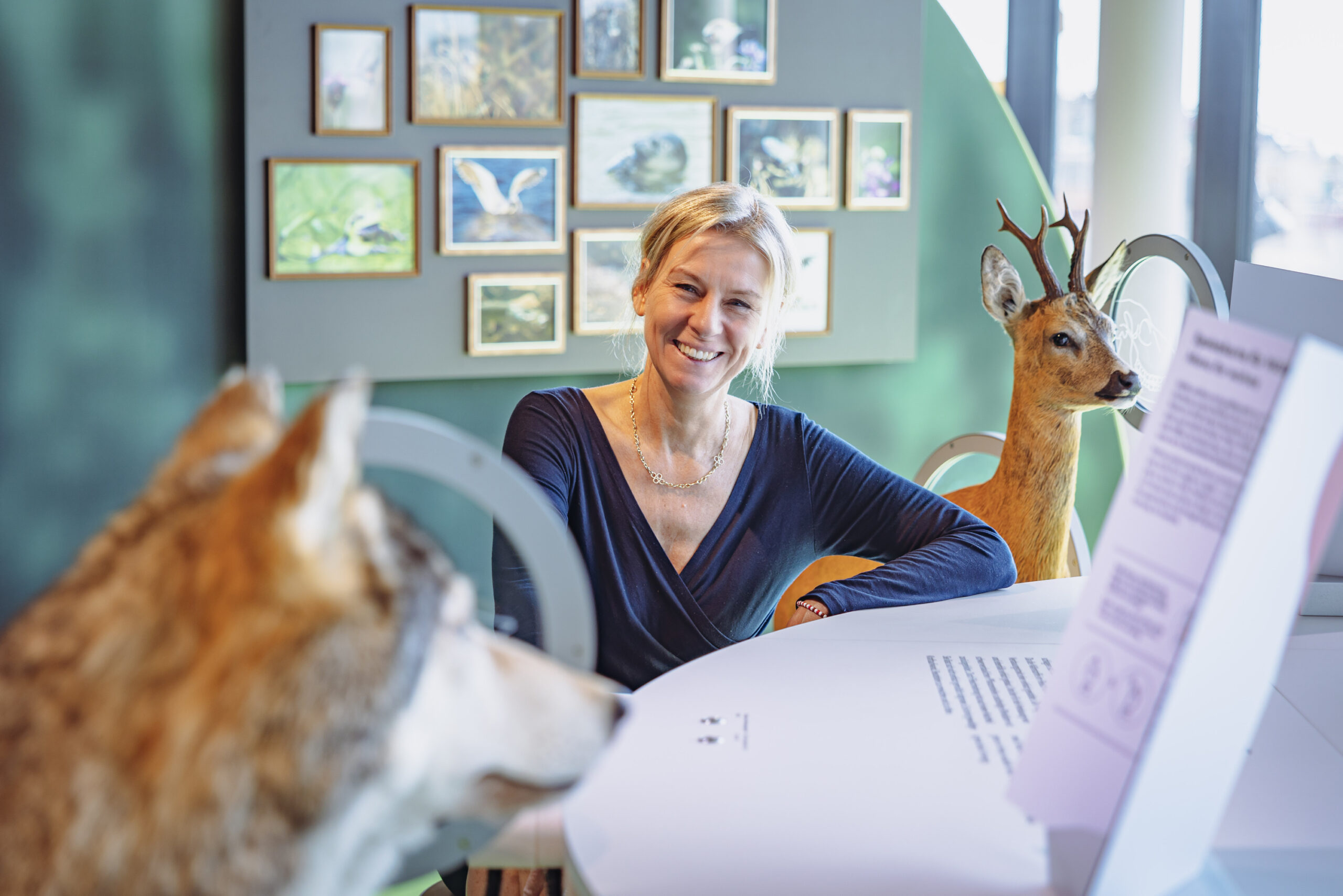 Blonde Frau lächelt neben einem Reh