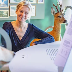 Blonde Frau lächelt neben einem Reh